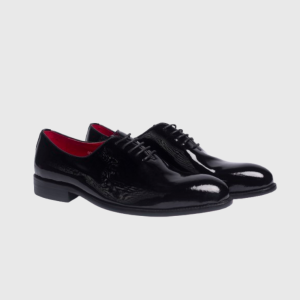 Black patent leather men's dress shoes with red interior lining on a white background.